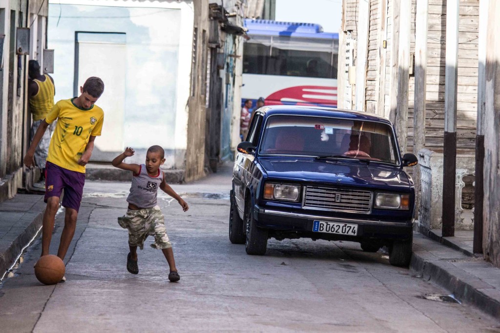 Children are playing with a ball near the car